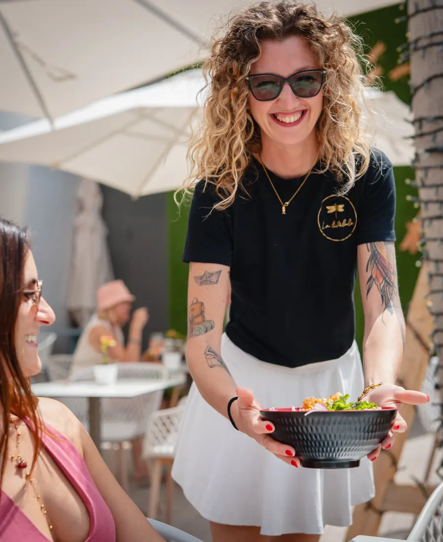Camarera sonriente sirve un bowl en la terraza