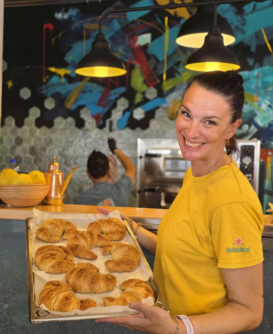 Chica del mostrador con una bandeja de cruasanes